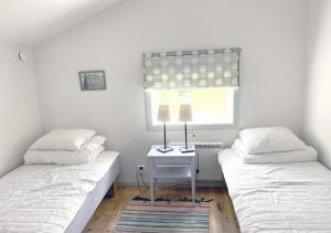 two beds in a room with a table and a window at Häradssätter gård 2 in Valdemarsvik +18 photos