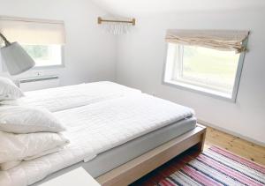 a white bedroom with a bed and a window at Häradssätter gård 2 in Valdemarsvik