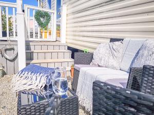eine Terrasse mit einem Sofa und einem Tisch mit einem Glas Wein in der Unterkunft Summer Breeze in Perranzabuloe