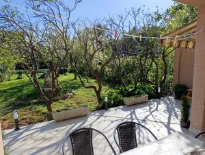 a patio with two chairs and a table and trees at Apartman Ladini Lana in Starigrad-Paklenica