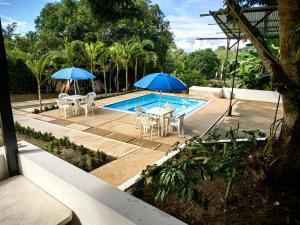 a pool with two umbrellas and a table and chairs at Villa Stefy in Carmen de Apicalá