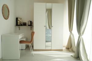 Park Room - Ischia Centro في ايسكيا: غرفة بها مرآة وكرسي بجوار نافذة