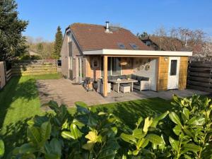 a house with a patio with a table and chairs at Bungalow Schotvanger in Egmond aan den Hoef