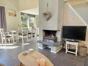 a living room with a fireplace and a tv at Bungalow Schotvanger in Egmond aan den Hoef
