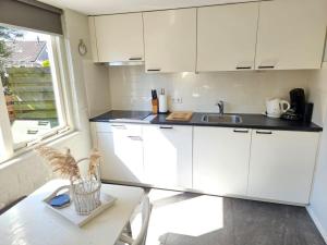 a kitchen with white cabinets and a table and a window at Bungalow Schotvanger in Egmond aan den Hoef