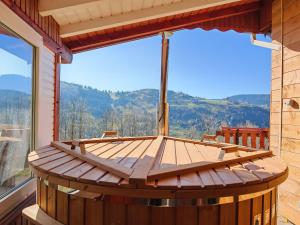 eine große Holzterrasse mit einem großen Fenster in der Unterkunft Chalet Toscane avec bain nordique in La Bresse