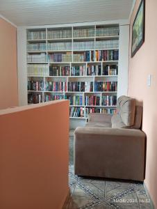 a living room with a couch and a book shelf with books at Hospede-se com conforto e vista privilegiada in Guaraqueçaba