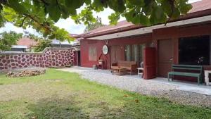 a red house with a green bench in the yard at BRUSSELS HOMESTAY BALIGE in Balige