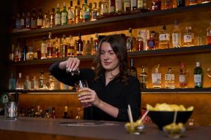 a woman sitting at a bar holding a glass at Sternen Hotel Wolfurt in Bregenz