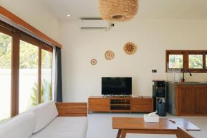 een woonkamer met een bank en een flatscreen-tv bij Villa Calma in Kuta Lombok