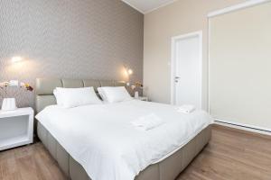 a white bedroom with a large bed with white sheets at Top City Center Apartment! in Budapest