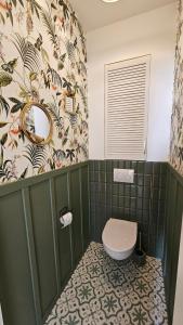 a bathroom with a toilet in a green tiled bathroom at House of the Sun in Ventspils