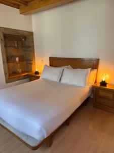 a bedroom with a large white bed with two night stands at Apartamentos Campanas de San Juan in Santiago de Compostela
