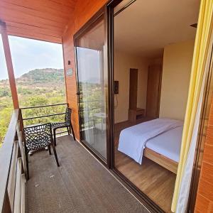 a bedroom with a bed and a balcony with a view at Bhairavnath Resort and Hospitality in Lonavala