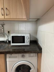 a kitchen with a microwave and a washing machine at Apartamentos Campanas de San Juan in Santiago de Compostela
