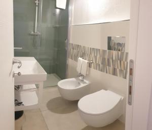a white bathroom with a toilet and a sink at Hotel La Palma in San Teodoro