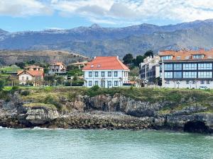 a group of houses on a cliff next to the water at Llanes Suites in Llanes