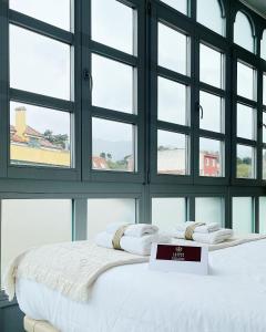 a bed with a sign on it in a room with windows at Llanes Suites in Llanes