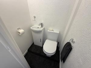 a small bathroom with a toilet and a sink at 3 bed Jct 37 M1 luxury stay! in Barnsley +10 photos