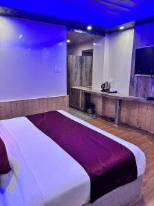 a large bed in a room with a tv at Shobha Hotel in Manāli