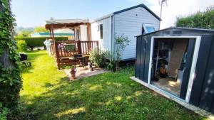 a backyard with a small house with a patio at Mobilhome in Saint-Arnoult
