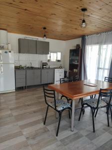 una cucina con tavolo e sedie in legno e una cucina con elettrodomestici bianchi di La Guarida a Pergamino