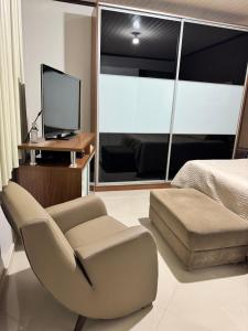 Un dormitorio con una cama y una silla y un televisor. en Casa para COP-30, en Castanhal