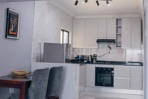 a kitchen with white cabinets and a table and chairs at The KWASU Apartments in Chipata