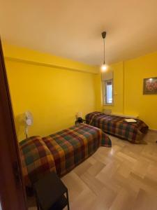 a room with two beds and yellow walls at Appartamento Vittoria in Grotte