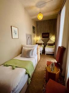 una habitación de hotel con dos camas y una silla en Riad La Calèche, en Marrakech