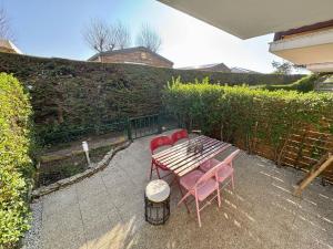 einen Holztisch und Stühle auf einer Terrasse in der Unterkunft Les Dunes - Jardin Privatif - Plage à 500 Mètres in Merville-Franceville-Plage + 10 Fotos