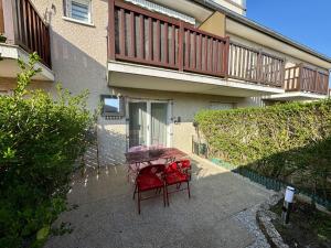 einem Tisch mit zwei roten Stühlen vor einem Gebäude in der Unterkunft Les Dunes - Jardin Privatif - Plage à 500 Mètres in Merville-Franceville-Plage