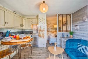 eine Küche mit einem Tisch und einem blauen Sofa in der Unterkunft Les Dunes - Jardin Privatif - Plage à 500 Mètres in Merville-Franceville-Plage