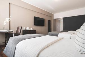 ein Hotelzimmer mit zwei Betten und einem Flachbildfernseher in der Unterkunft Hotel Tolosa in Puerto Madryn