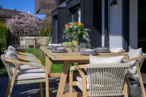 een houten tafel met stoelen en een vaas met bloemen bij BergHome in Garmisch-Partenkirchen