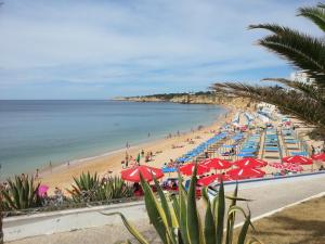 a beach with many umbrellas and people on it at Armador Apartment in Armação de Pêra