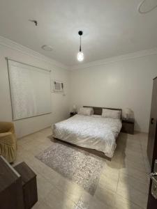a white bedroom with a bed and a rug at شقة أنيقة بالزاهر غرفتين وصالة in Makkah