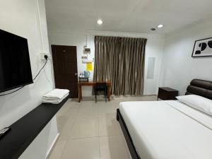 a bedroom with a bed and a desk with a television at Lan Village in Mersing