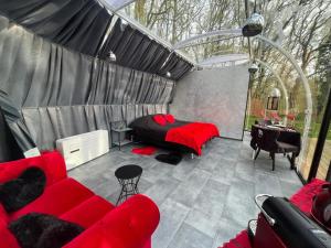 a bedroom with a red couch and a bed in a tent at Bulle Love Passion & Spa in Escamps
