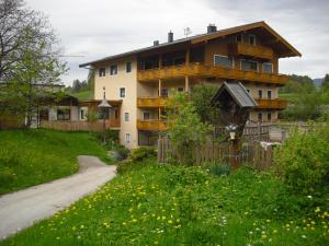 ein Haus mit einem Zaun neben einer unbefestigten Straße in der Unterkunft Häringer Mühle in Bad Häring