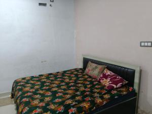 ein Schlafzimmer mit einem Bett mit einer Decke und Kissen in der Unterkunft Abhay Paying Guest House in Ayodhya