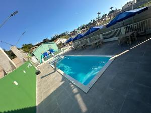 a swimming pool with tables and umbrellas on a patio at Portal Araticum Flats in Bonito