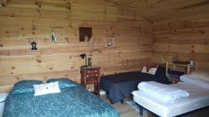 a bedroom with two beds in a log cabin at Gîte - La Ferme à la Plage in Le Porge