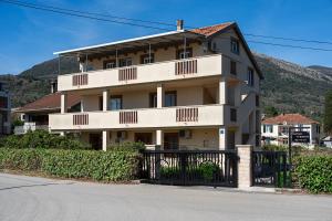 a large white building with a fence in front of it at Apartments Ivo Bozinovic in Tivat