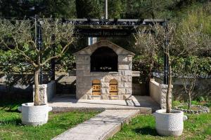 a stone fireplace with two trees in a yard at Apartments Ivo Bozinovic in Tivat