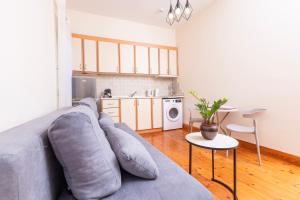 a living room with a gray couch and a kitchen at Mouragia Budget Places in Corfu Town