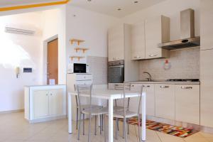 a kitchen with white cabinets and a white table and chairs at Andrea's House in Locri +35 photos