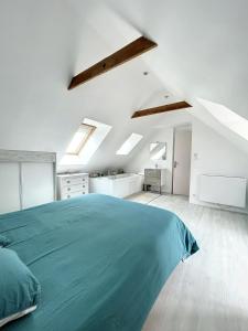 a white bedroom with a green bed and skylights at Beau duplex et studio proche de la mer in Donville-les-Bains