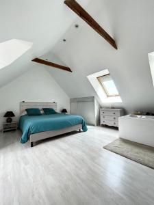 een witte slaapkamer met een bed en een dakraam bij Beau duplex et studio proche de la mer in Donville-les-Bains