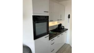 a kitchen with white cabinets and a black oven at Deck 29 in Timmendorfer Strand